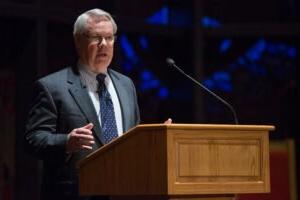 Dr. George Knight standing behind the podium giving a lecture